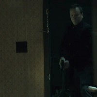 Kiefer Sutherland in The Confession kicking down door holding gun